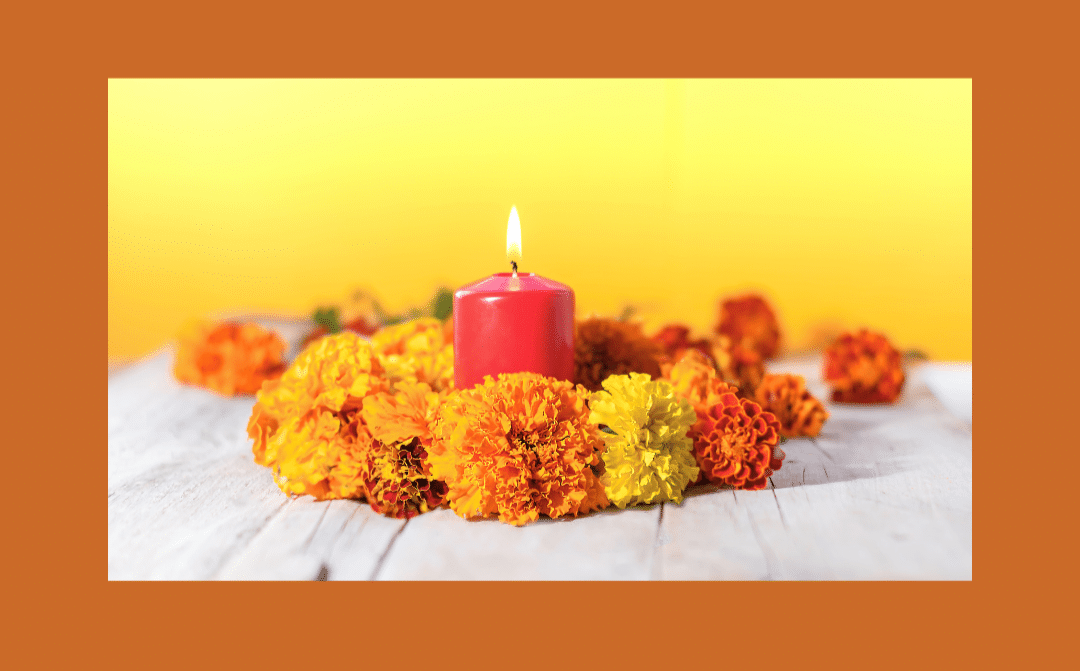 Une couronne de fleurs aux tons orangés et jaunes avec une bougie en son centre pour une décoration thème automne qui rapelle dia de muerto