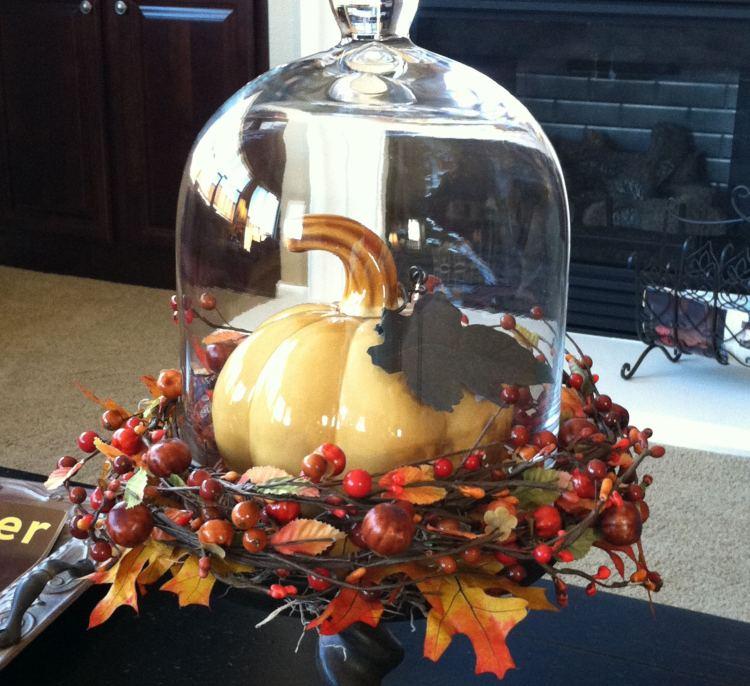 Photo d'une cloche style cabinet de curiosité pour une décoration thème automne avec une citrouille en porcelaine et une couronne de baies et de feuillage